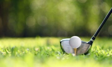 Golf ball on green grass ready to be struck on golf course background